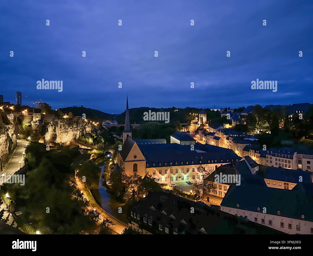 Paesaggio urbano europeo con chiesa storica e edifici illuminati nell'ora blu del crepuscolo. Vista ad alta angolazione di una città storica europea al crepuscolo feat Foto Stock