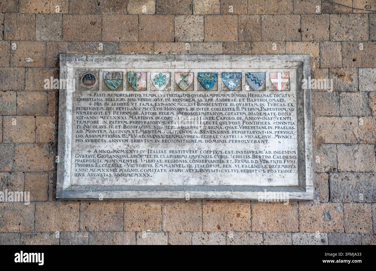 Placca commemorativa in pietra con stemmi nobiliari e iscrizioni storiche nel portico di Sant'Andrea, Orvieto, Umbria, Italia Foto Stock