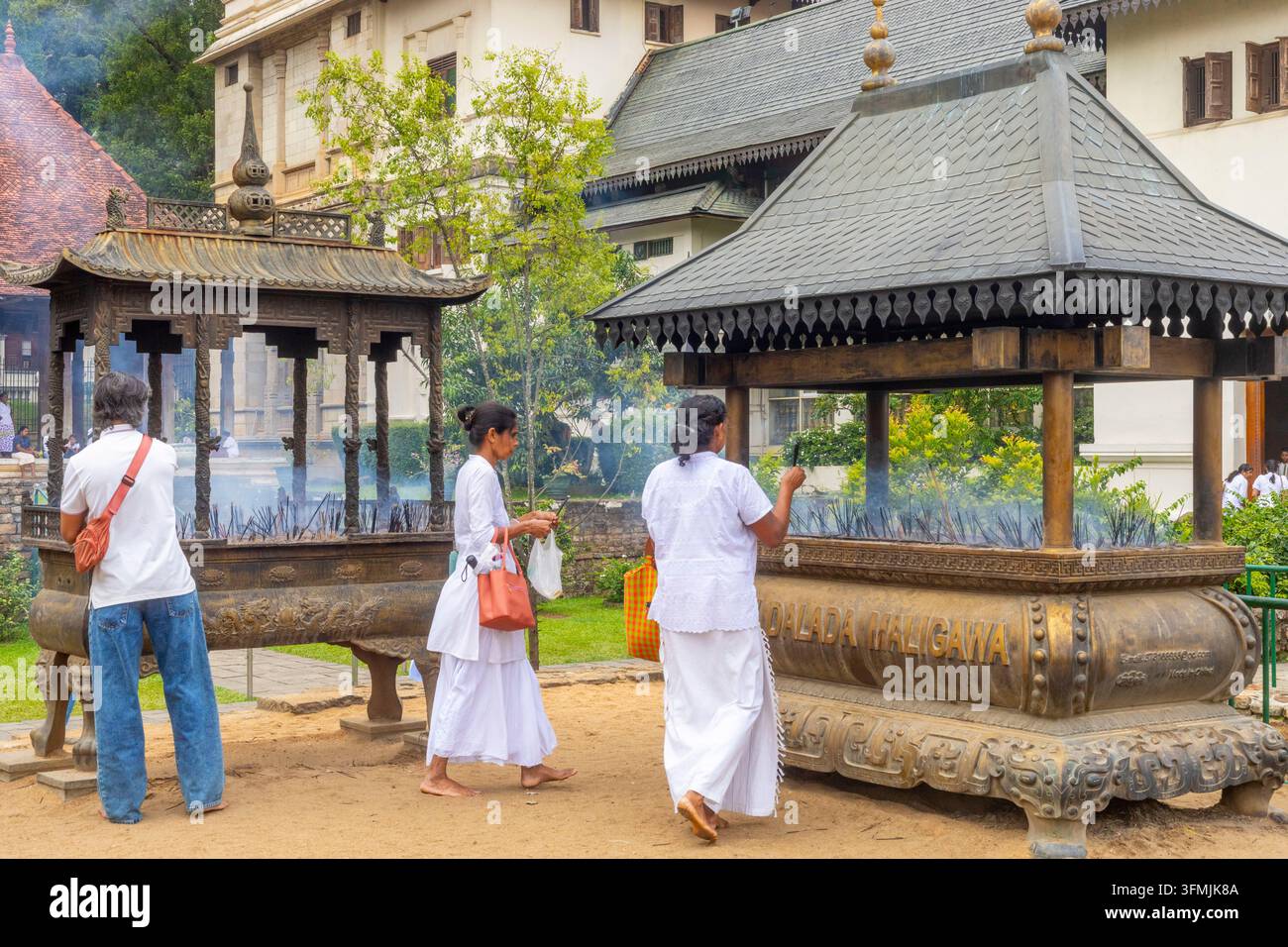 Sri Lanka, Kandy, Sri Dalada Maligawa (Tempio della Sacra Reliquia del Dente) – un sito del patrimonio mondiale UNESCO – che mostra un rituale in cui i fedeli pongono bastoncini di incenso in un bruciatore di bronzo Foto Stock