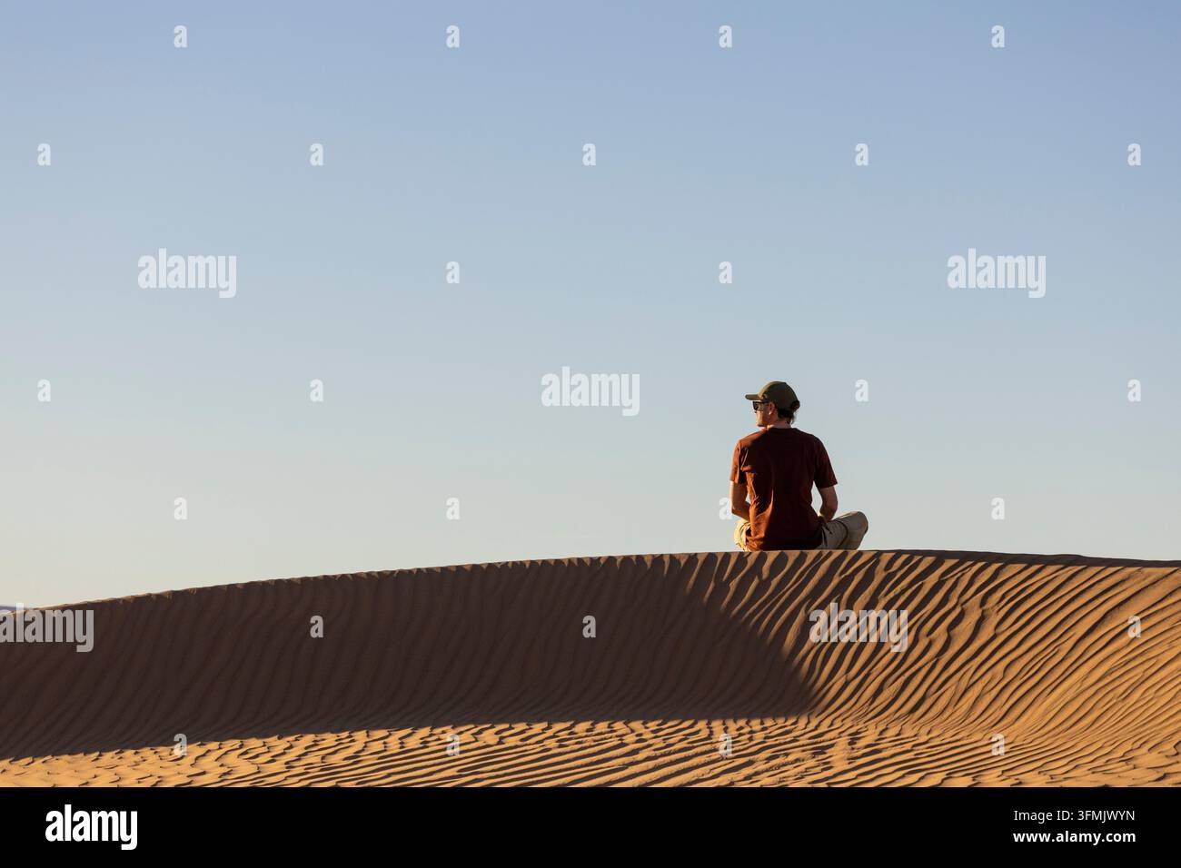 Marocco, regione di Drâa-Tafilalet, provincia di Zagora, valle del Draa, deserto di Zagora, uomo seduto su una duna Foto Stock