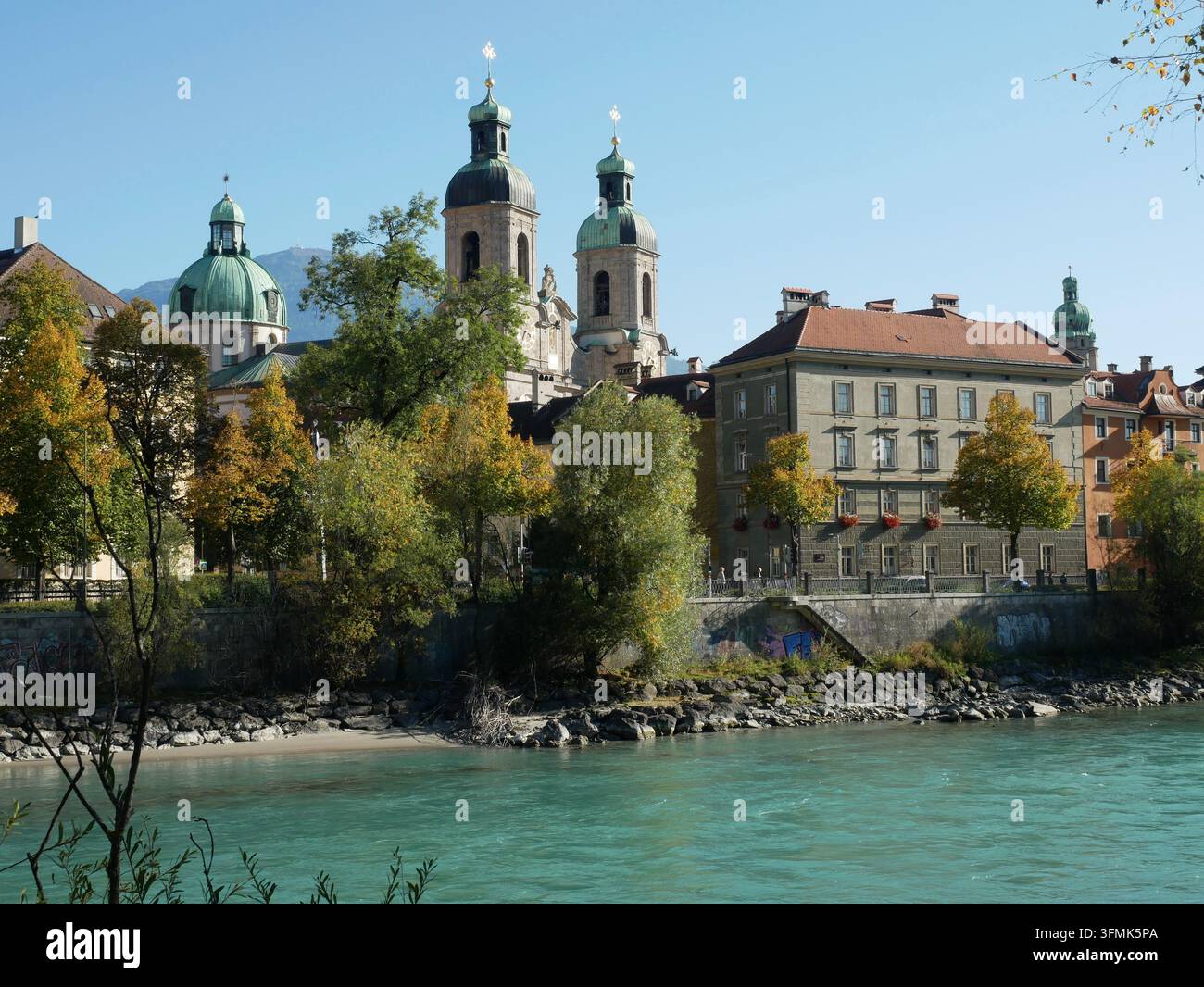 Le torri gemelle e la cupola della Cattedrale di San Giacomo si ergono sopra l'architettura storica sul lungofiume e le acque turchesi dell'Inn a Innsbruck, A Foto Stock