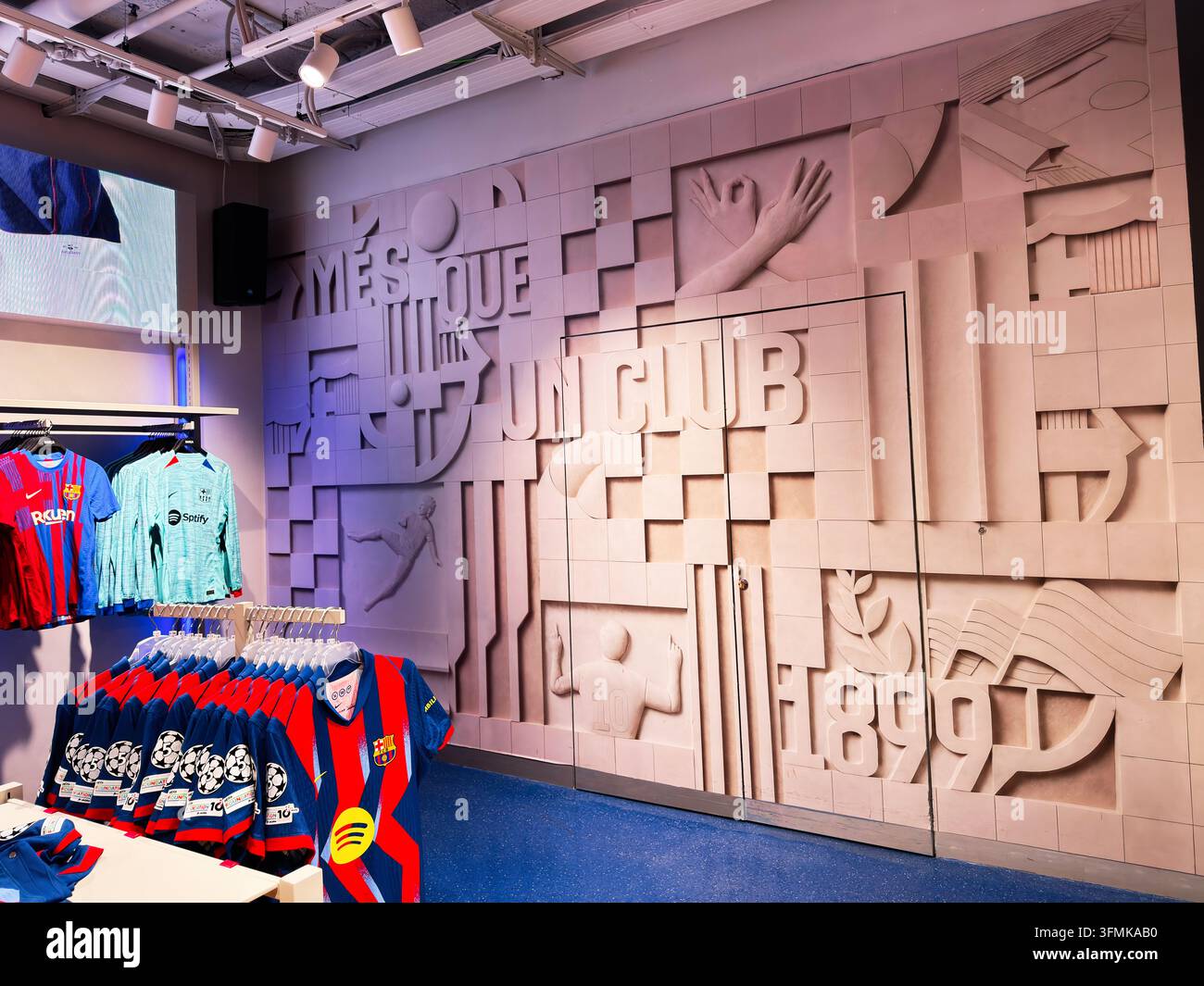 Barcellona, Spagna – 26 giugno 2026: Interno di negozio con maglie del FC Barcellona, scaffali di merchandising e un murale scolpito che celebra l'identità del club Foto Stock