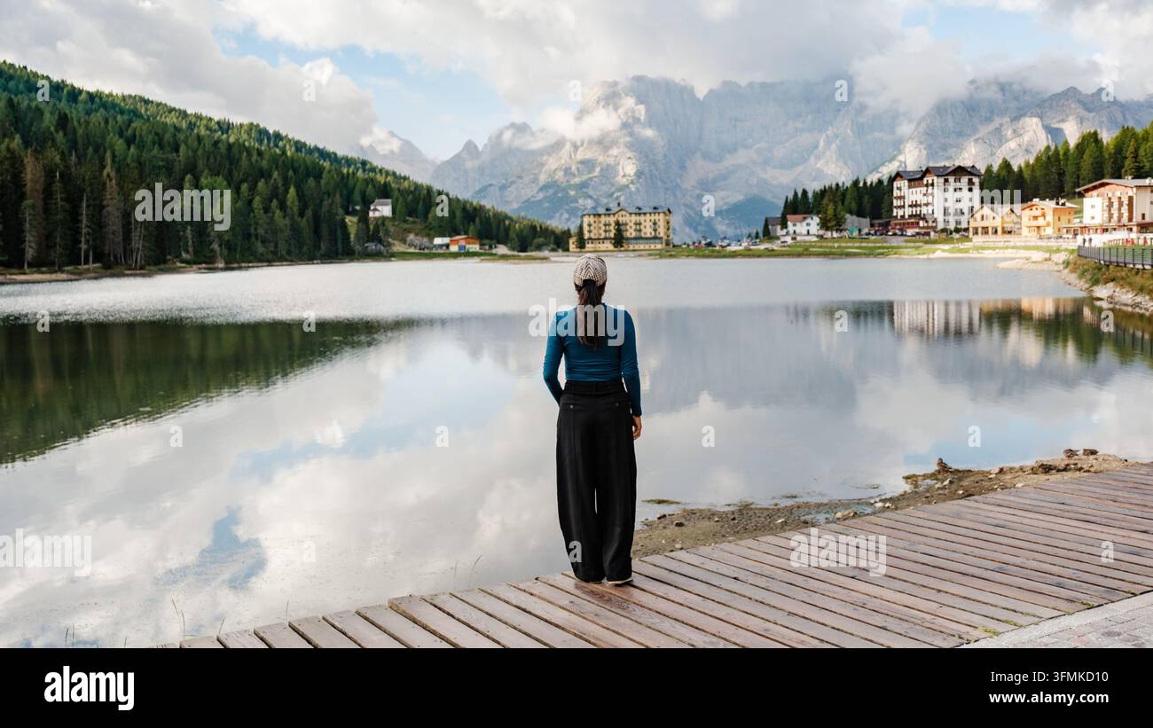 Una scena serena al Lago di Misurina, dove un viaggiatore ammira i riflessi mozzafiato delle maestose Dolomiti in Italia. Il paesaggio si dispiega wi Foto Stock