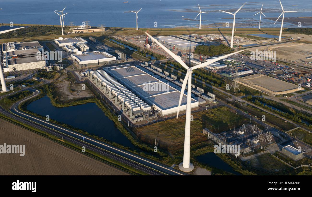 Vista aerea di un grande centro dati circondato da turbine eoliche, campi verdi e infrastrutture costiere a Eemshaven, Groningen, Paesi Bassi Foto Stock
