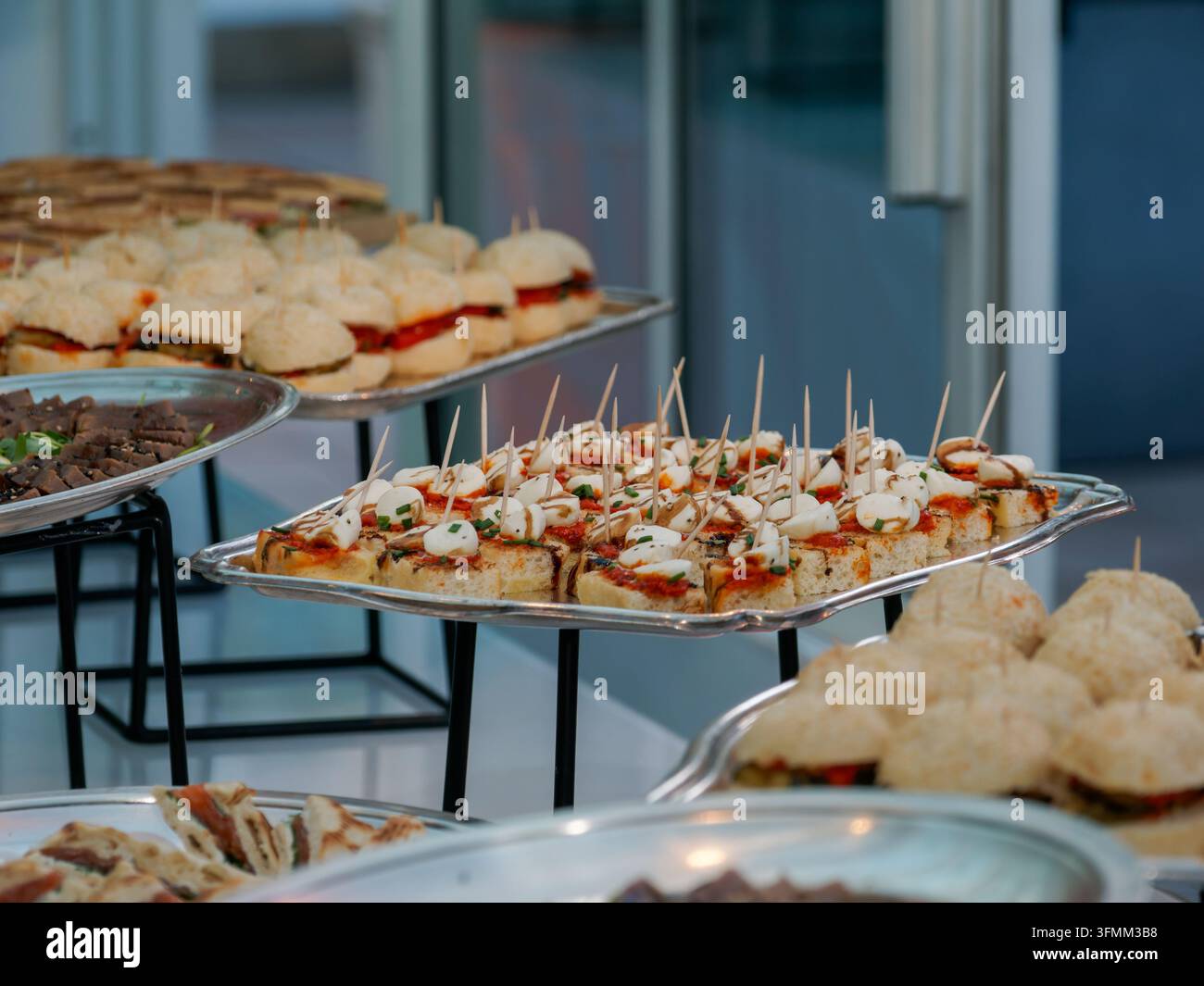 Piatto di finger food assortiti tra cui mini panini e antipasti con formaggio e pomodoro su spiedini. Foto Stock