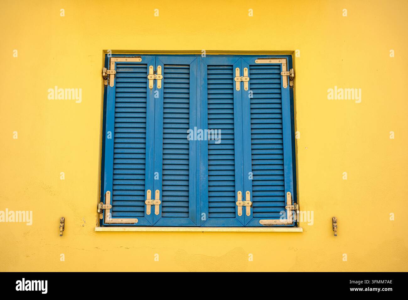 Persiane blu su un muro giallo Foto Stock