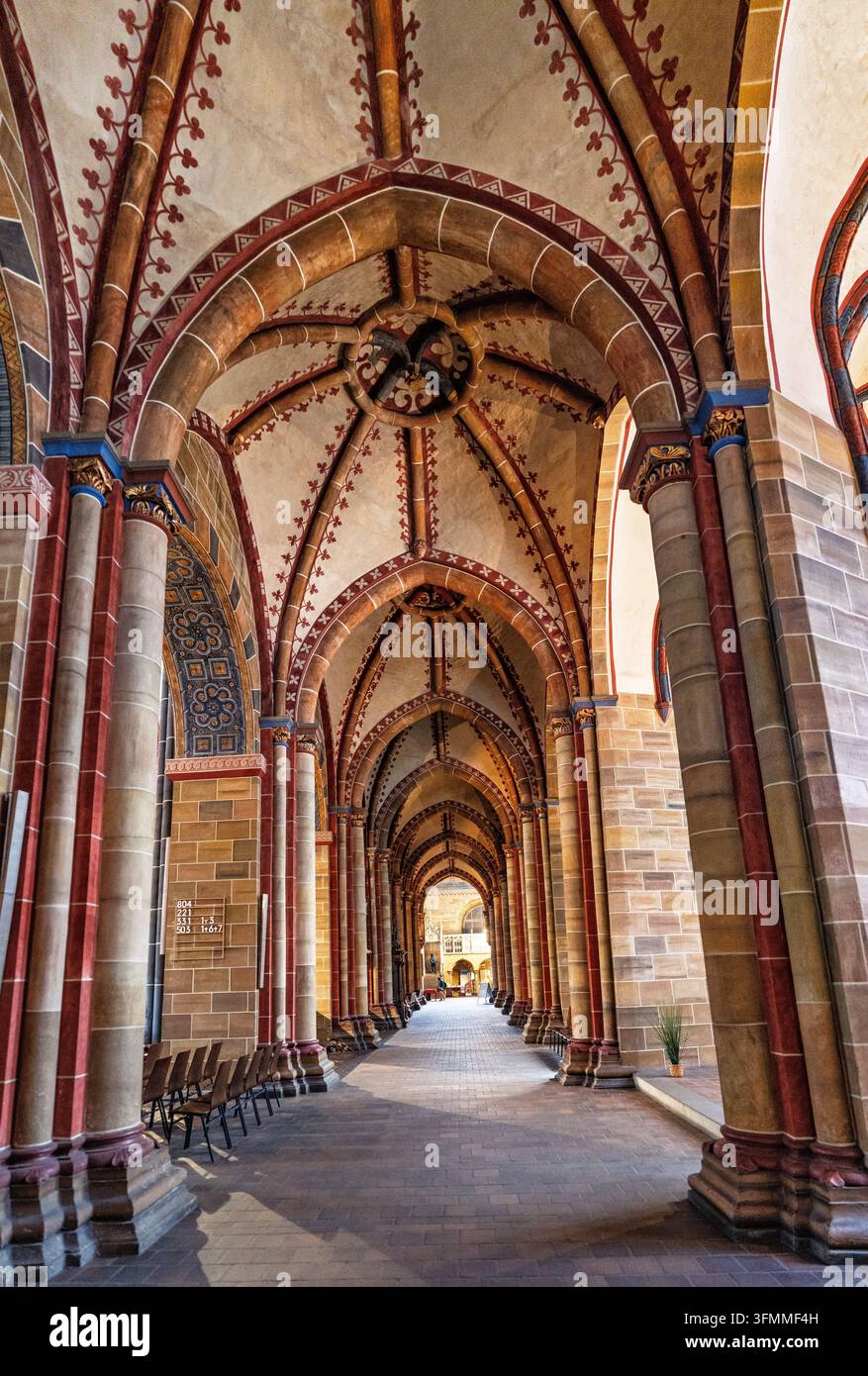 Chiostro in stile medievale illuminato dal sole che mostra intricate lavorazioni in pietra e archi simmetrici. Foto Stock