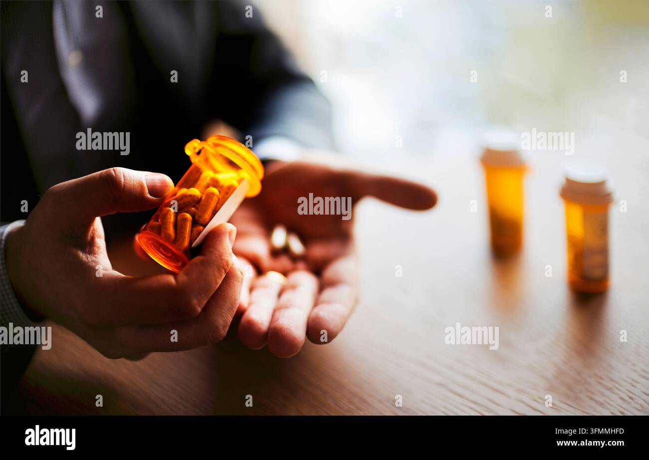 Mani tengono una bottiglia di medicina su ricetta arancione sopra un palmo aperto, mentre due contenitori simili appaiono sfocati su un tavolo di legno Foto Stock
