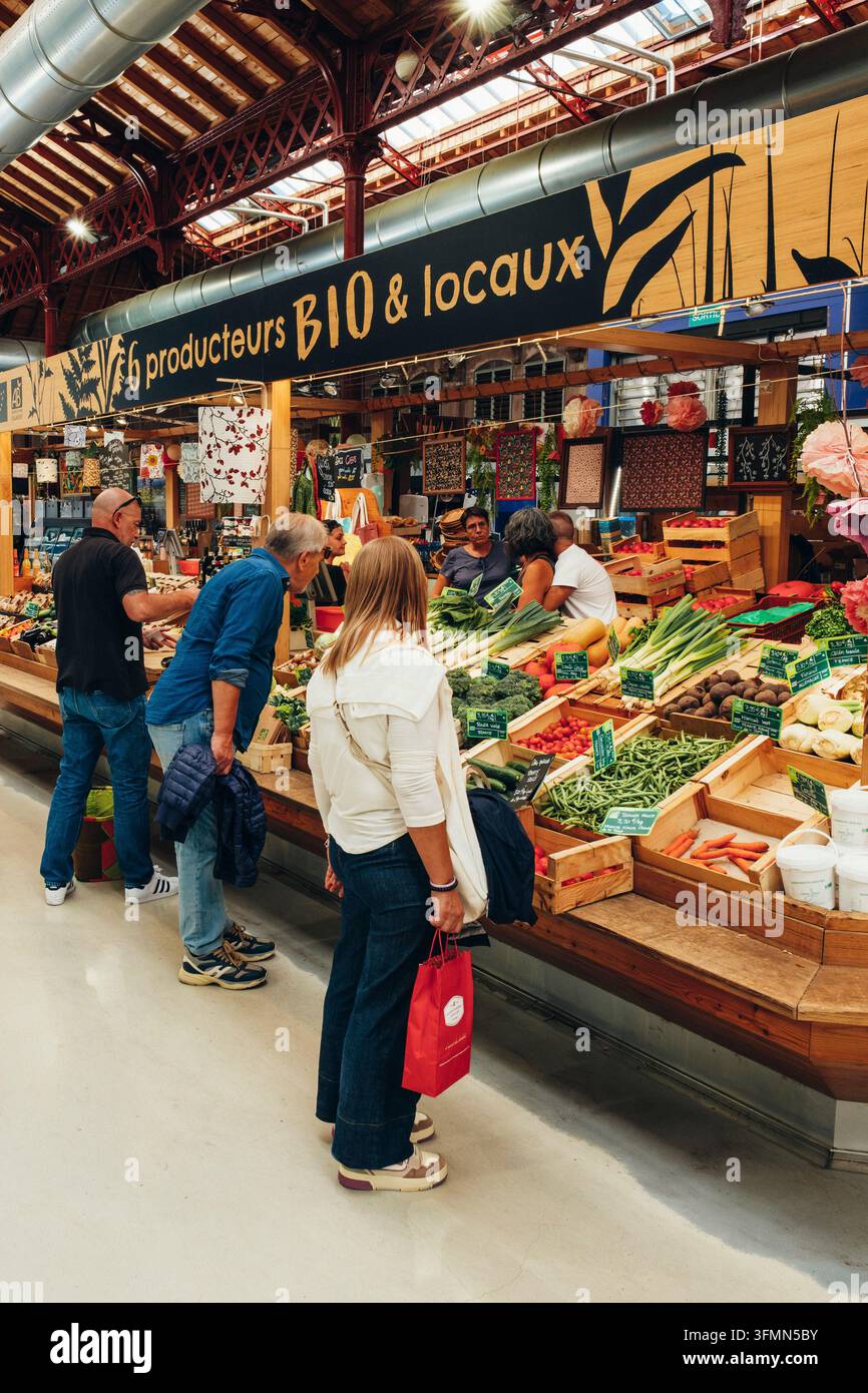 Banchetto di mercato ben frequentato dell'associazione di produttori Producteurs Bio & Locaux all'interno della storica sala del mercato coperta. Il focus è su c Foto Stock