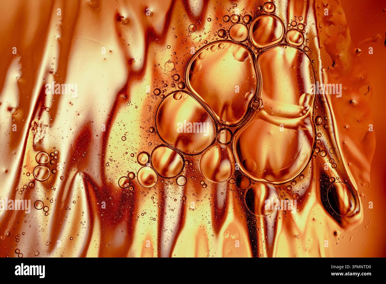 Sfondo astratto liquido dorato con bolle di olio e gocce d'acqua che creano texture e motivi intricati Foto Stock