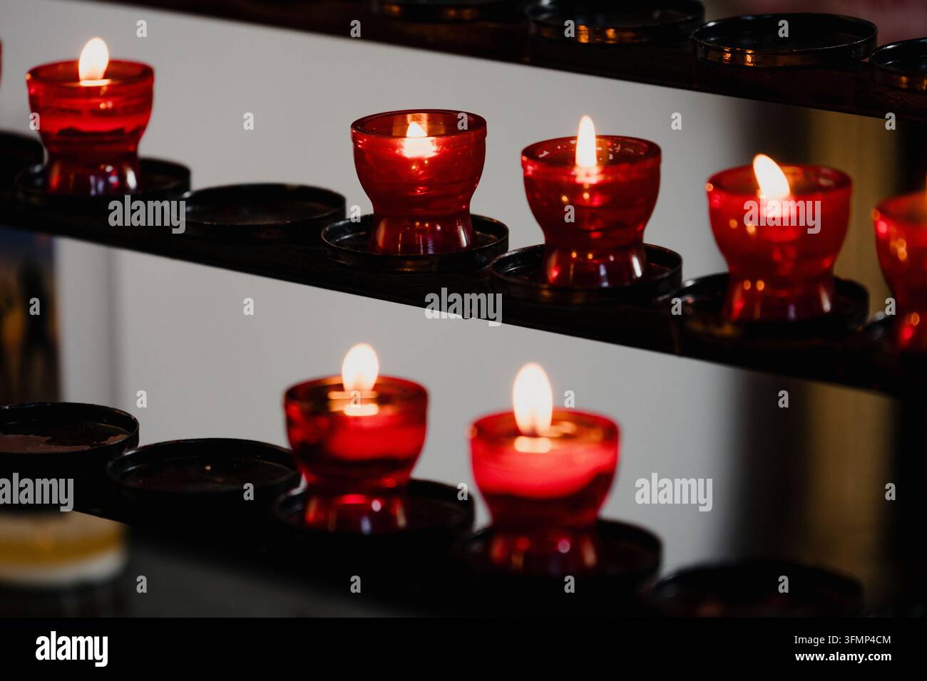 Candele rosse brucianti in una chiesa per il ricordo e la preghiera Foto Stock