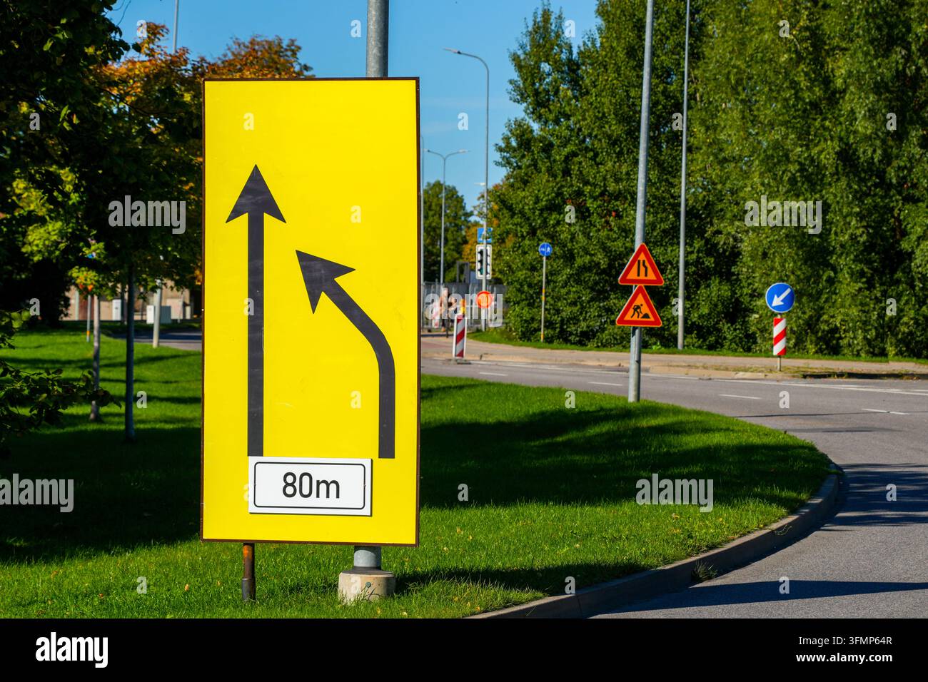 Segnale stradale temporaneo giallo che avverte di un cambio di corsia tra 80 metri durante i lavori stradali urbani Foto Stock