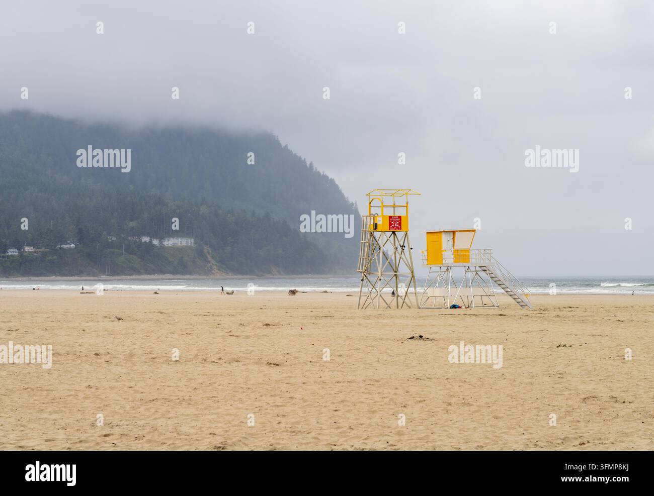 Torri di guardia gialli si ergono sulla spiaggia sabbiosa di Seaside, nella contea di Clatsop, Oregon, con la nebbiosa Testa di Tillamook che si erge sopra l'oceano. Foto Stock