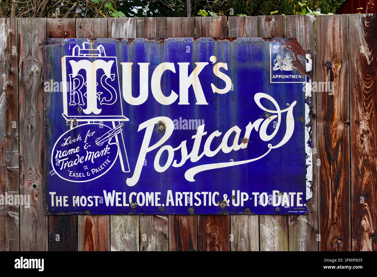 Insegna in smalto blu per Raphael Tuck and Sons Tuck's Postcards su recinzione di legno Foto Stock