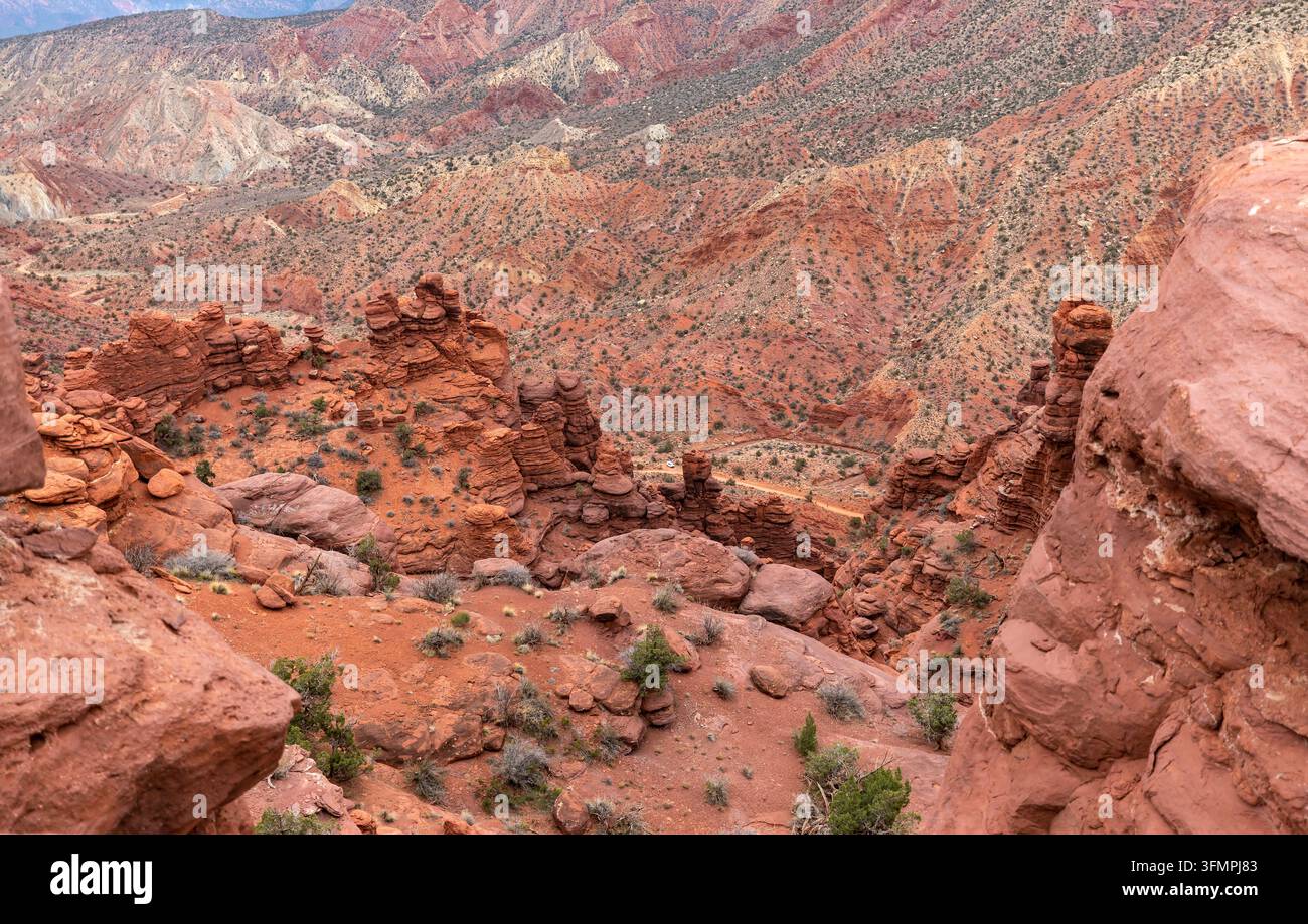 Aree desertiche di rocce rosse colorate con hoodoo di arenaria erosi e una strada sterrata sinuosa che si estende sotto la fine del sentiero Fisher Towers vicino a Moab, Utah, USA Foto Stock