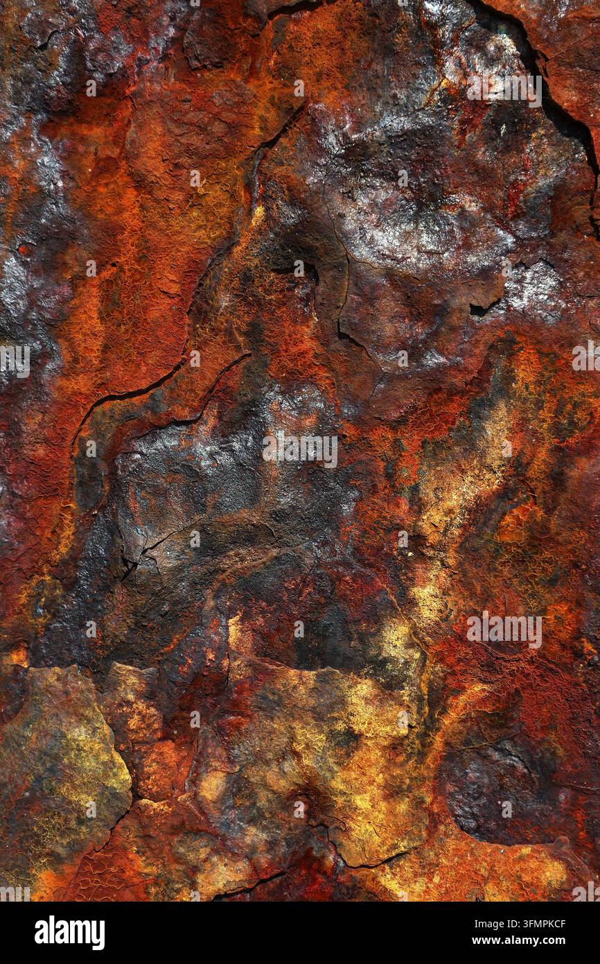 Primo piano astratto di metallo consumato coperto da ossido arrugginito, patina scura, crepe e variazioni di colore simili a minerali, creando uno sfondo industriale drammatico Foto Stock