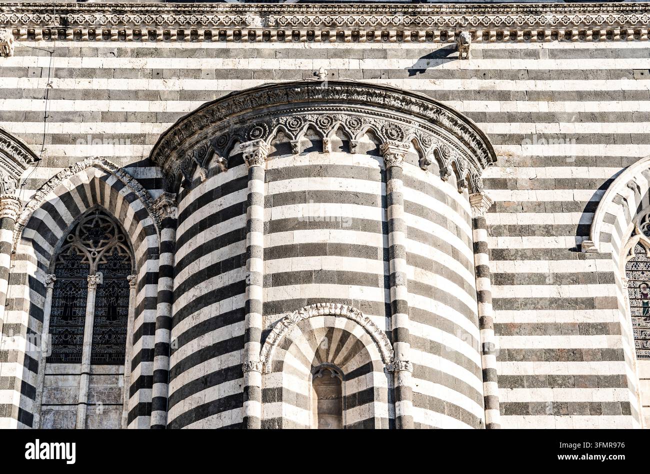 Elevazione laterale suggestiva della Cattedrale di Orvieto con bande alternate di marmo bianco e scuro, colonne scolpite e absidi semicircolari sporgenti, Orvieto Foto Stock