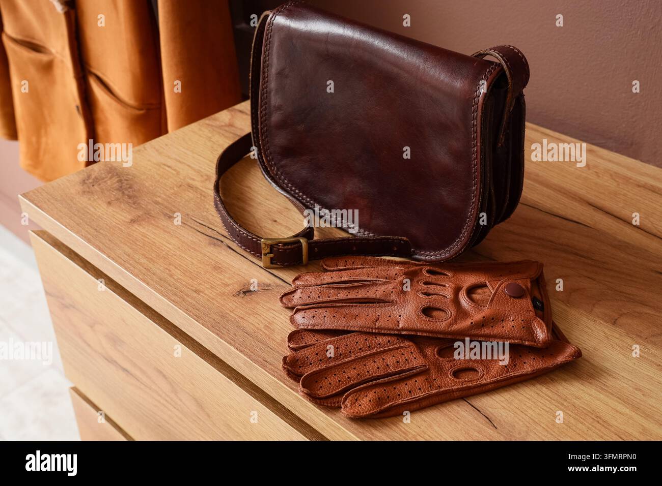Moda lenta e stile di vita sostenibile, borsa in pelle vintage e guanti da guida su un comò in legno per uno stile classico e accessori di lusso Foto Stock