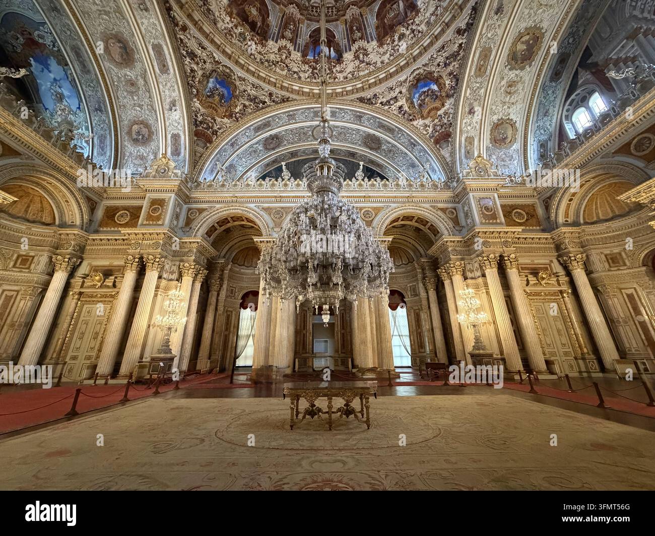 Una vista simmetrica della grande Sala Cerimoniale, lampadario di cristallo, colonne e cupola decorata all'interno del Palazzo Dolmabahçe, Istanbul, Türkiye. - Immagine stock catturata con smartphone