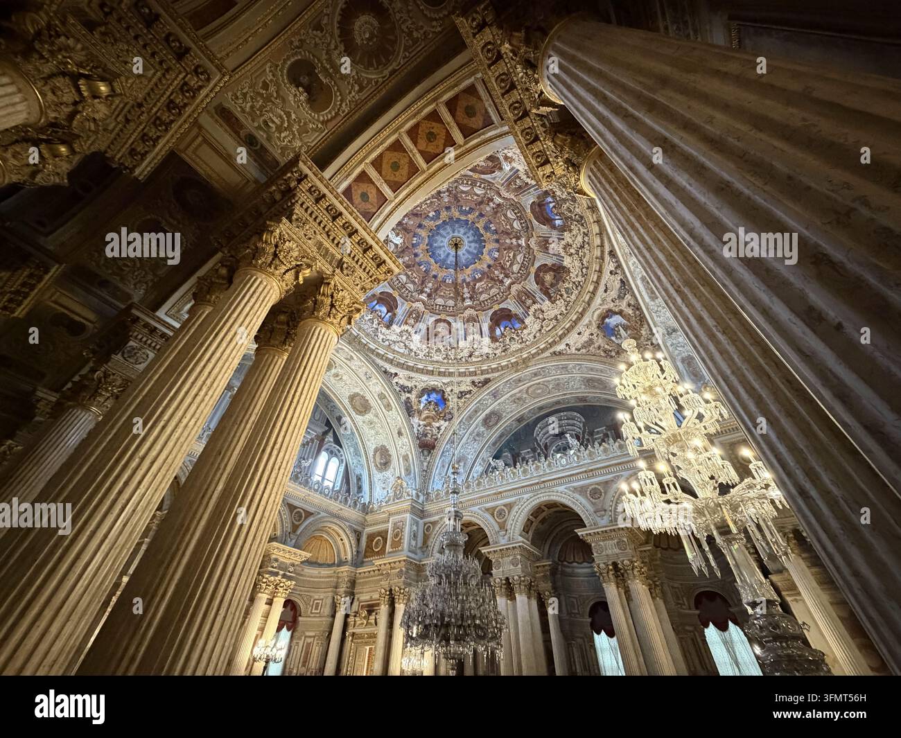 Una vista verso l'alto attraverso le colonne di marmo rivela la cupola decorata e i lampadari di cristallo della Sala delle Cerimonie del Palazzo di Dolmabahçe, a Istanbul. - Immagine stock catturata con smartphone