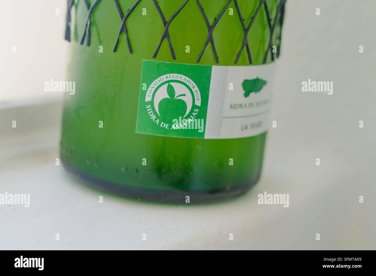 Aviles, Spagna – 27 settembre 2026. Primo piano di una bottiglia di sidro verde con l'etichetta del Consejo Regulador DOP Sidra de Asturias e il numero di serie. Cibo Foto Stock