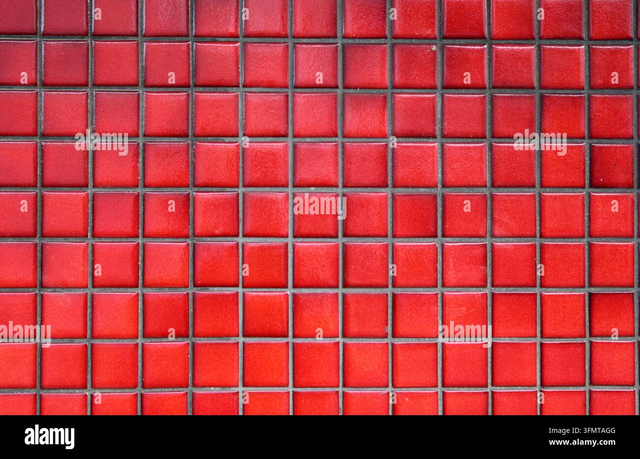Trama a tutto schermo di piccole piastrelle di mosaico ceramiche rosse quadrate con giunti scuri che formano una griglia geometrica ordinata Foto Stock