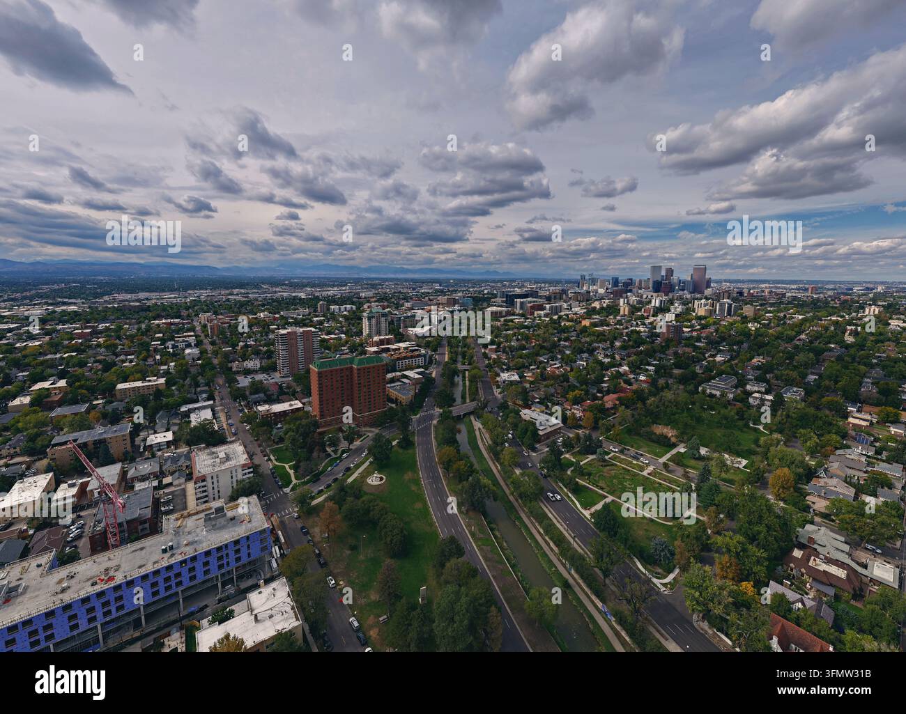 Vista aerea di Cherry Creek che si snoda attraverso il paesaggio urbano con lo skyline di Denver sullo sfondo sotto un cielo nuvoloso a Denver, Colorado, Unità Foto Stock