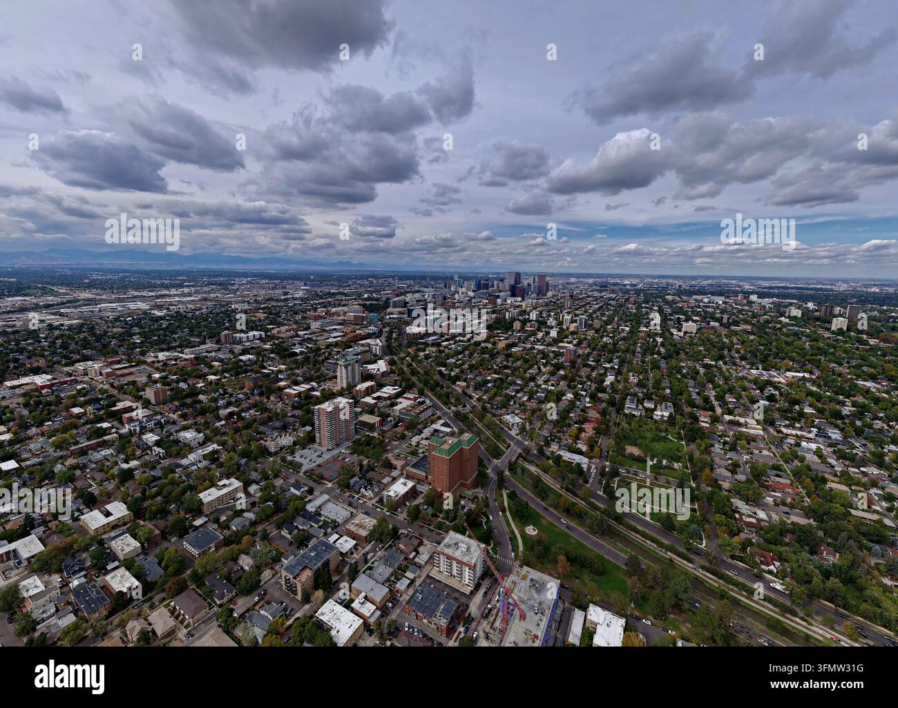 Veduta aerea del quartiere di Cherry Creek con densi complessi residenziali, strade fiancheggiate da alberi rigogliosi e lo skyline lontano del centro di Denver und Foto Stock
