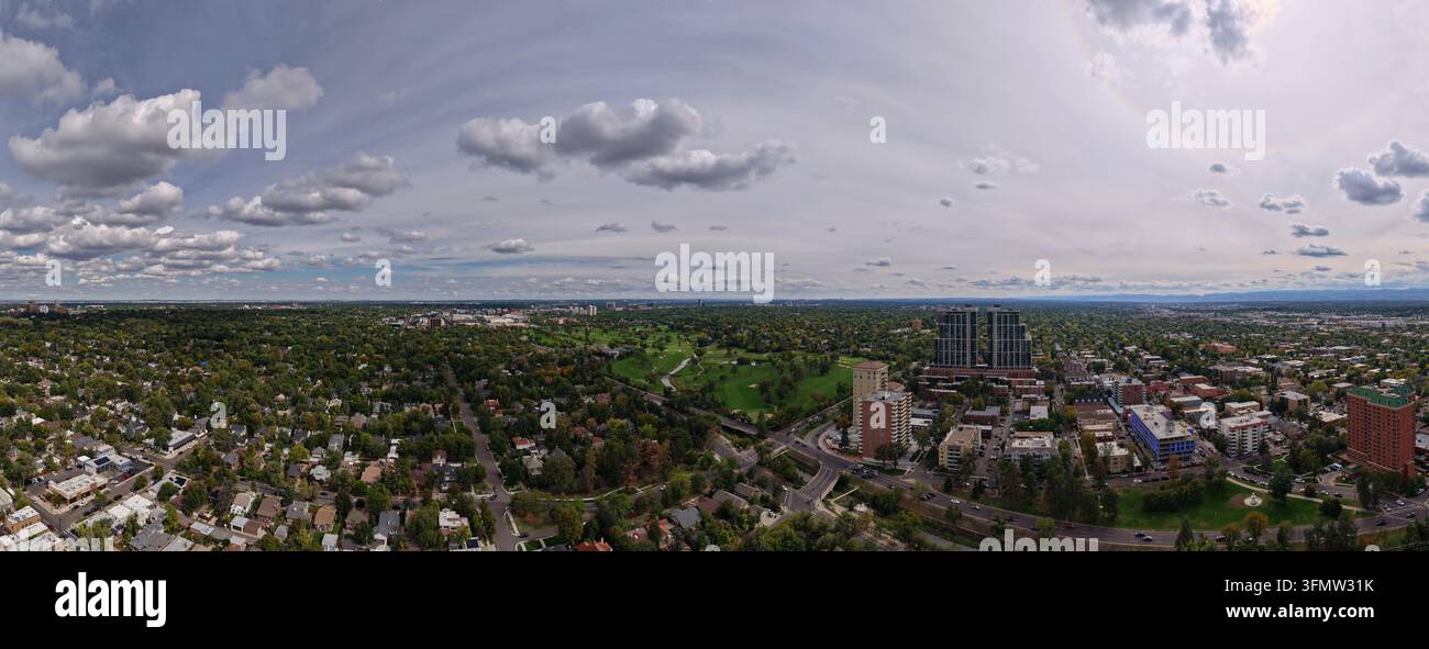 Veduta aerea di Cherry Creek che si snoda attraverso il paesaggio urbano con alberi rigogliosi, grattacieli e quartieri residenziali sotto un cielo nuvoloso Foto Stock