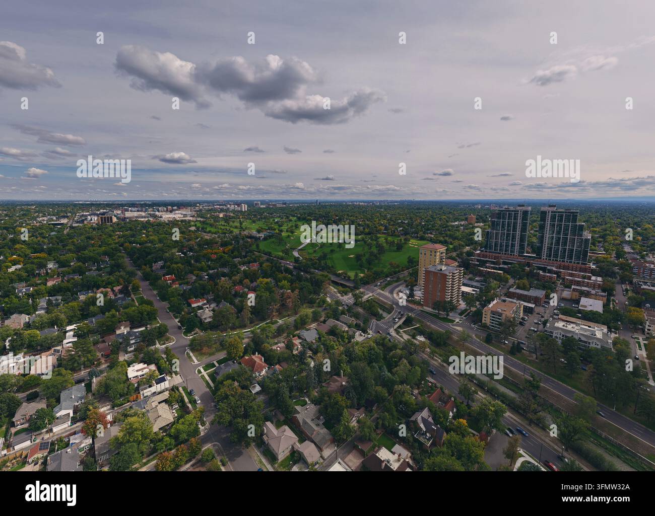 Vista aerea di Cherry Creek a Denver, con parchi verdi, sentieri tortuosi, quartieri residenziali e moderni grattacieli sotto un cielo nuvoloso Foto Stock