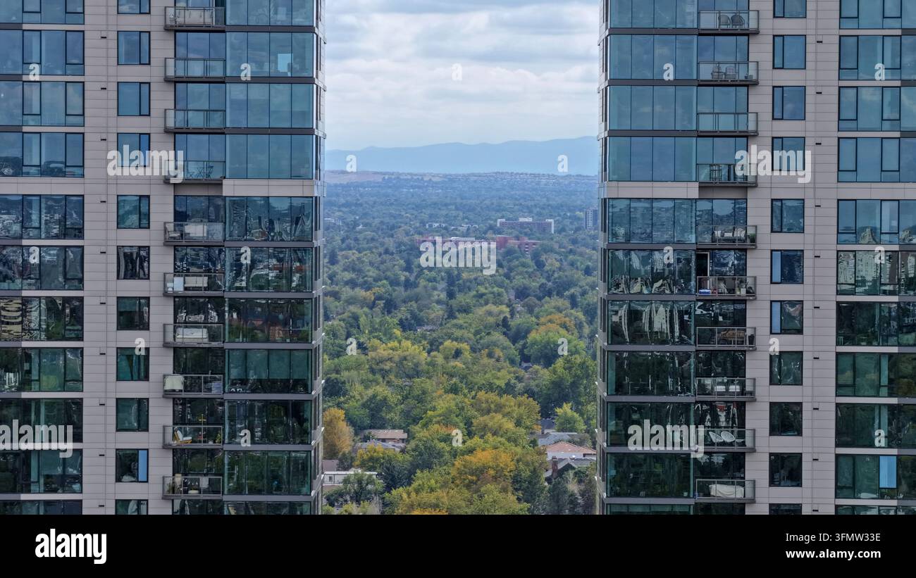 Vista aerea di Cherry Creek incorniciata da grattacieli moderni in vetro con balconi, che si affaccia su alberi verdi rigogliosi e il paesaggio urbano di Denver, Colorado, U Foto Stock