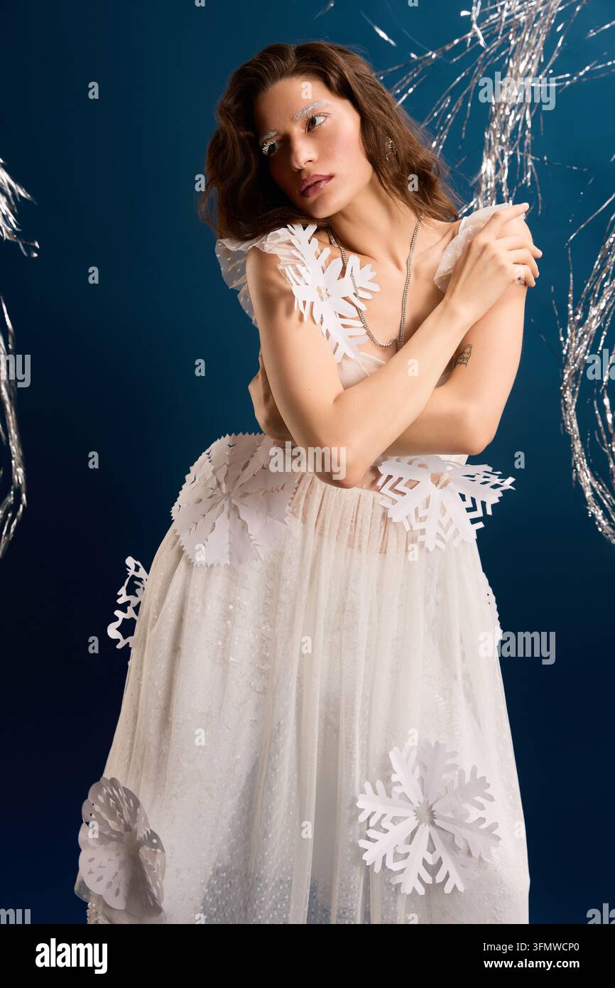 Una bella giovane donna posa elegantemente in un abito a tema festivo, emanando fascino invernale. Foto Stock