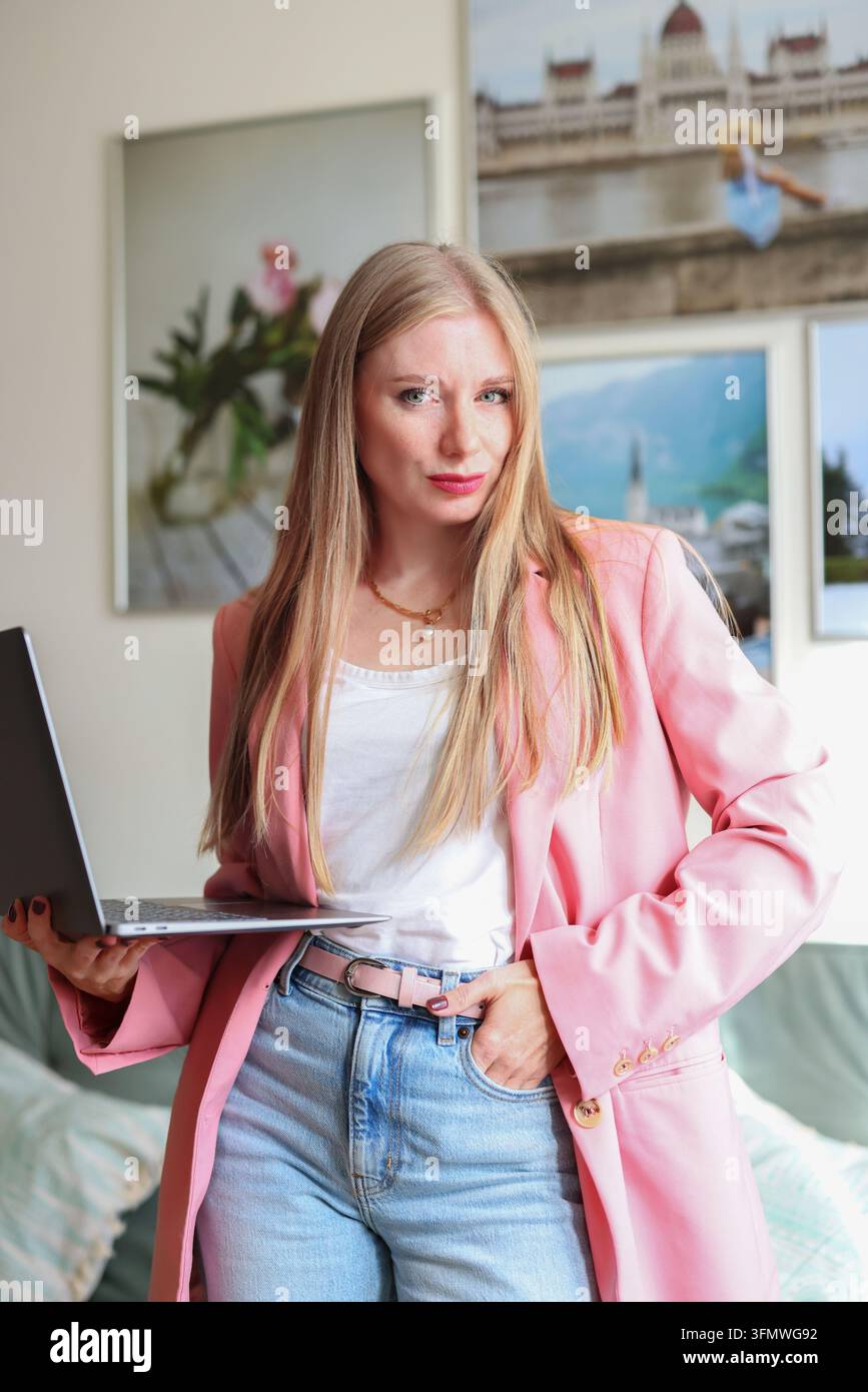 Imprenditrice felice lavora con un laptop, ideale per concetti di business online, branding personale e successo professionale. Foto Stock