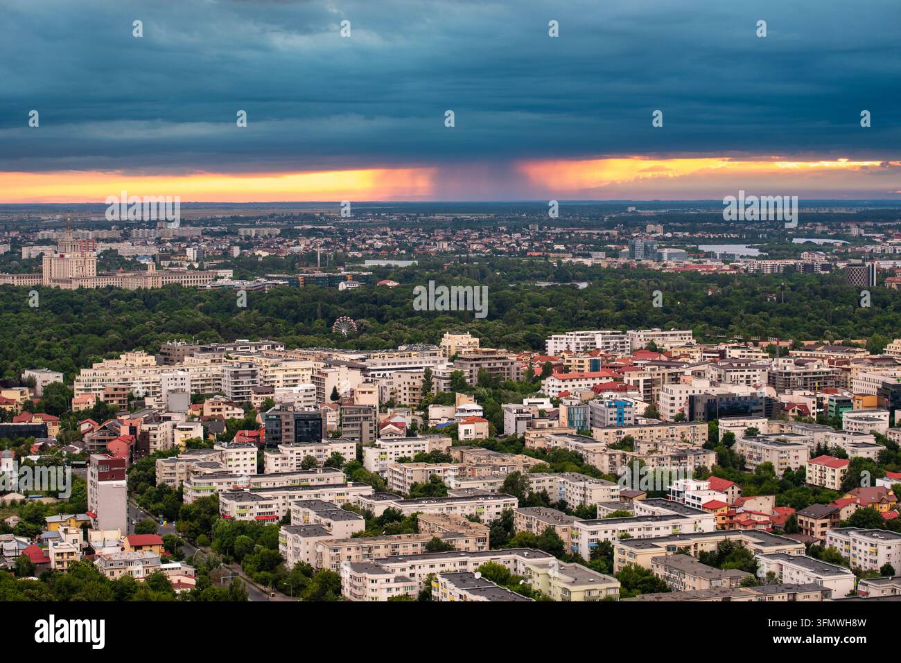 Vista della skyline di Bucarest sotto un drammatico cielo tempestoso con la luce del tramonto che illumina l'orizzonte sopra edifici residenziali e spazi verdi a Bu Foto Stock