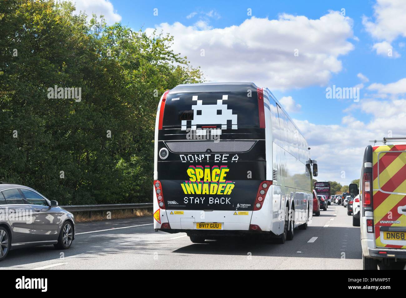 Retro di un pullman National Express sull'autostrada britannica con adesivo della campagna "Don't Be a Space Invader, Stay Back" contro il distanziamento insufficiente di National Highways. Foto Stock