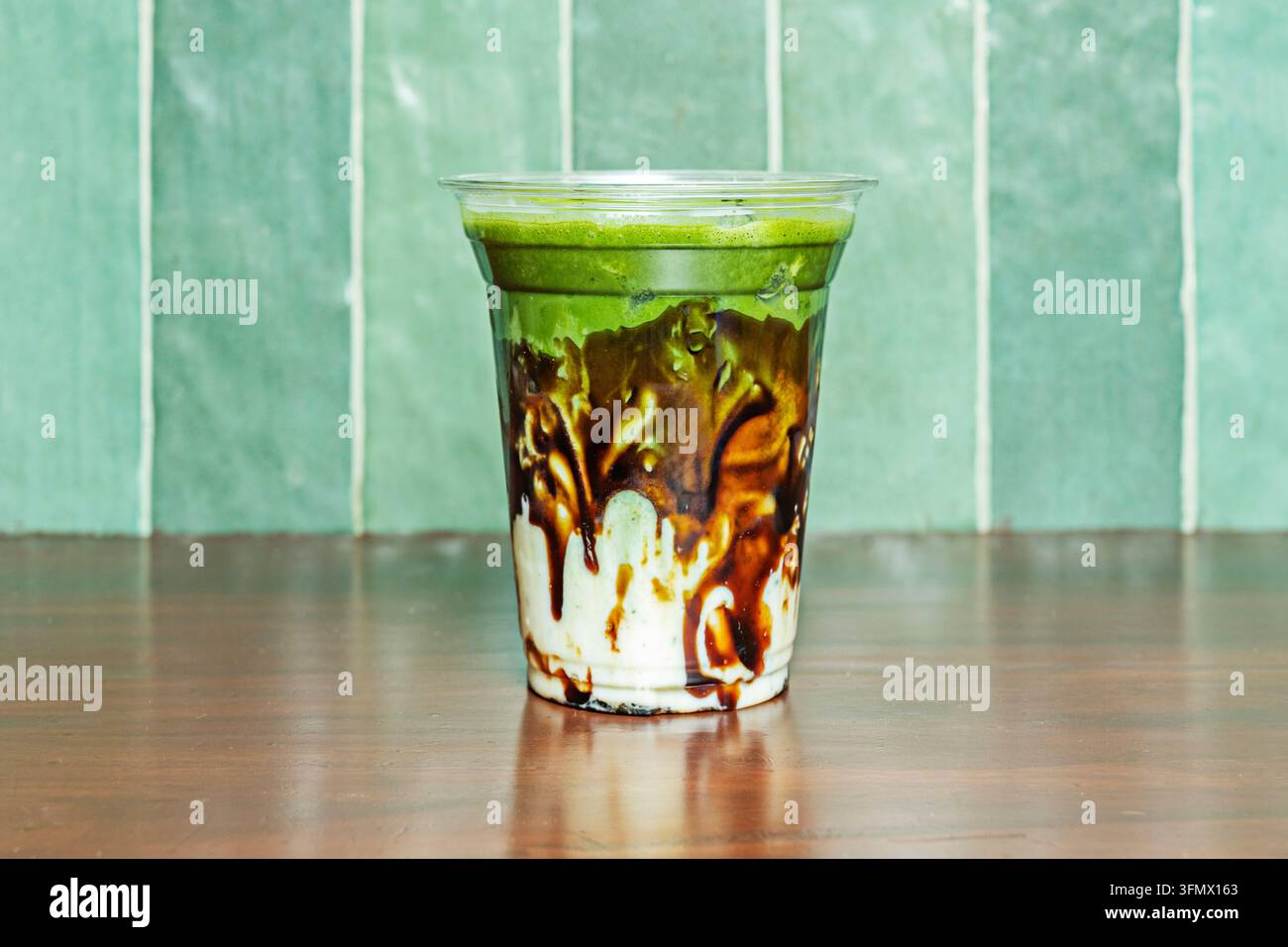 Bevanda ghiacciata al matcha con salsa di caramello che cola lungo una tazza trasparente Foto Stock