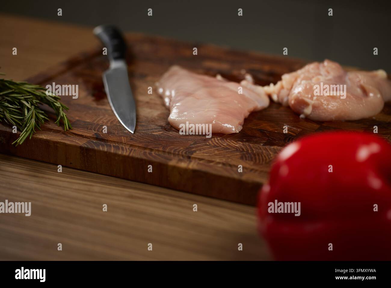 Filetti di pollo crudi su tagliere con coltello Foto Stock