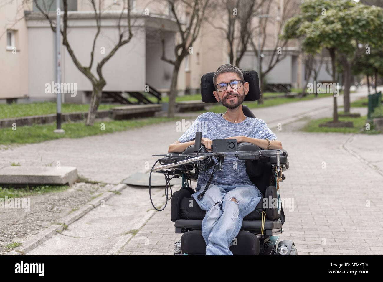 Ritratto di un uomo disabile seduto su una sedia a rotelle su un sentiero in area urbana. Foto Stock