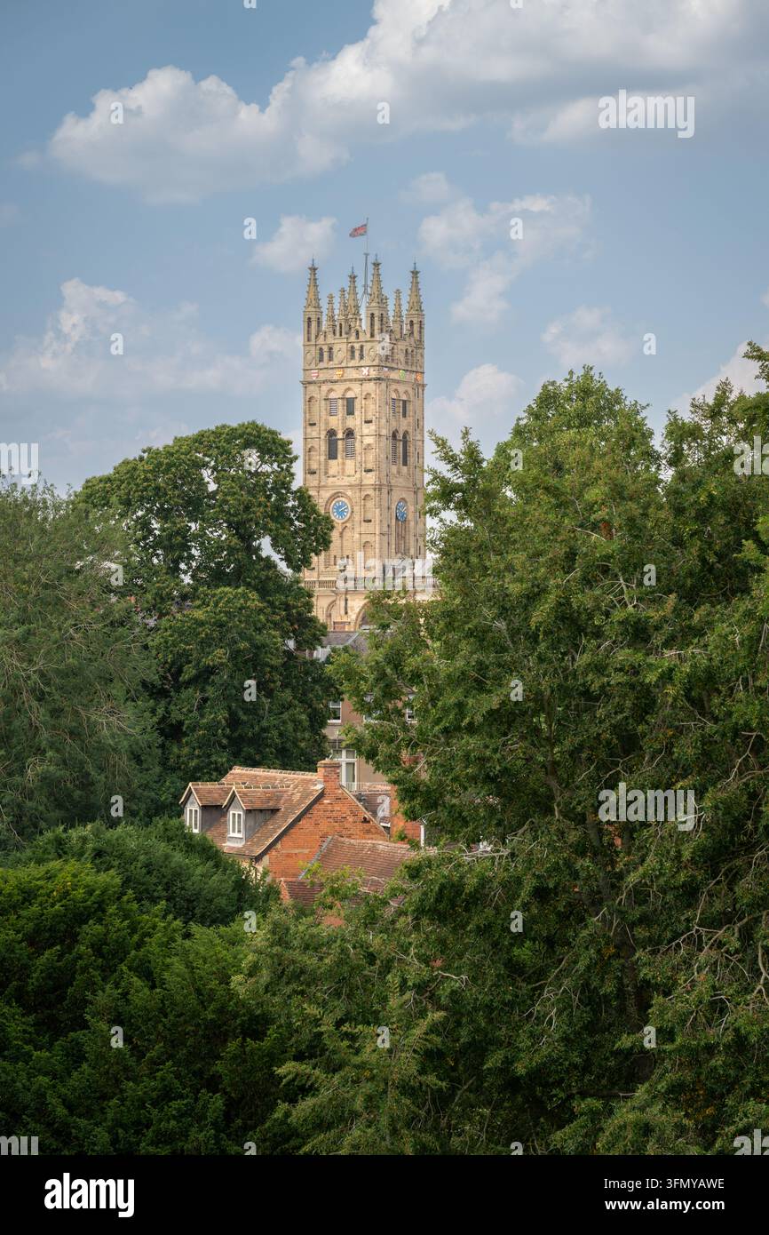 La torre della chiesa di St Mary, Warwick, Regno Unito. Vista dalle mura del castello di Warwick con alberi in primo piano. Foto Stock