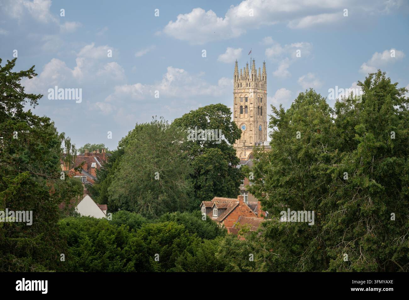 La torre della chiesa di St Mary, Warwick, Regno Unito. Vista dalle mura del castello di Warwick con alberi in primo piano. Foto Stock