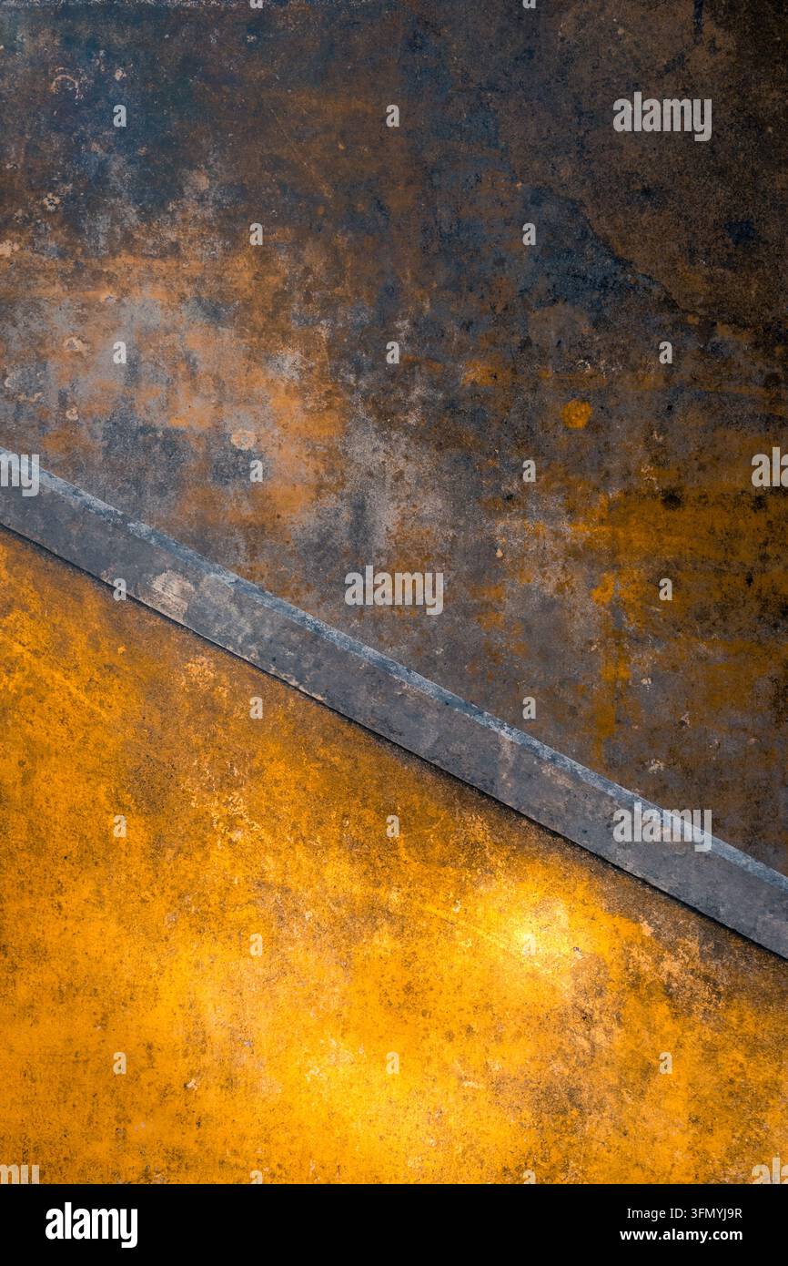 Primo piano astratto di una superficie metallica arrugginita e consumata nelle tonalità di arancione, marrone e grigio, divisa da una striscia d'acciaio diagonale. Sfondo industriale invecchiato Foto Stock