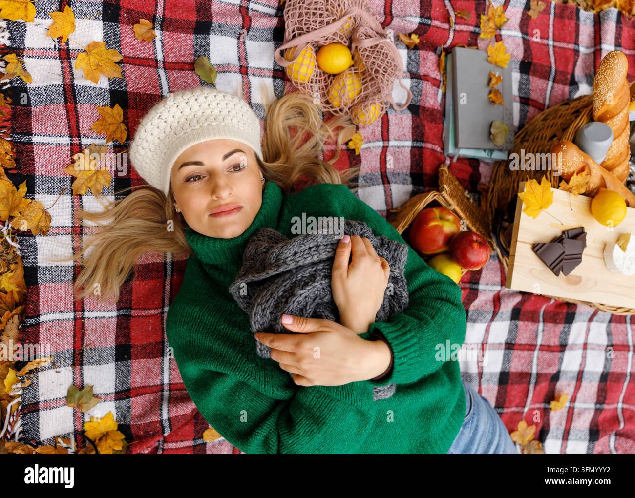 Donna che stende una coperta da picnic sulle foglie autunnali nel parco Foto Stock