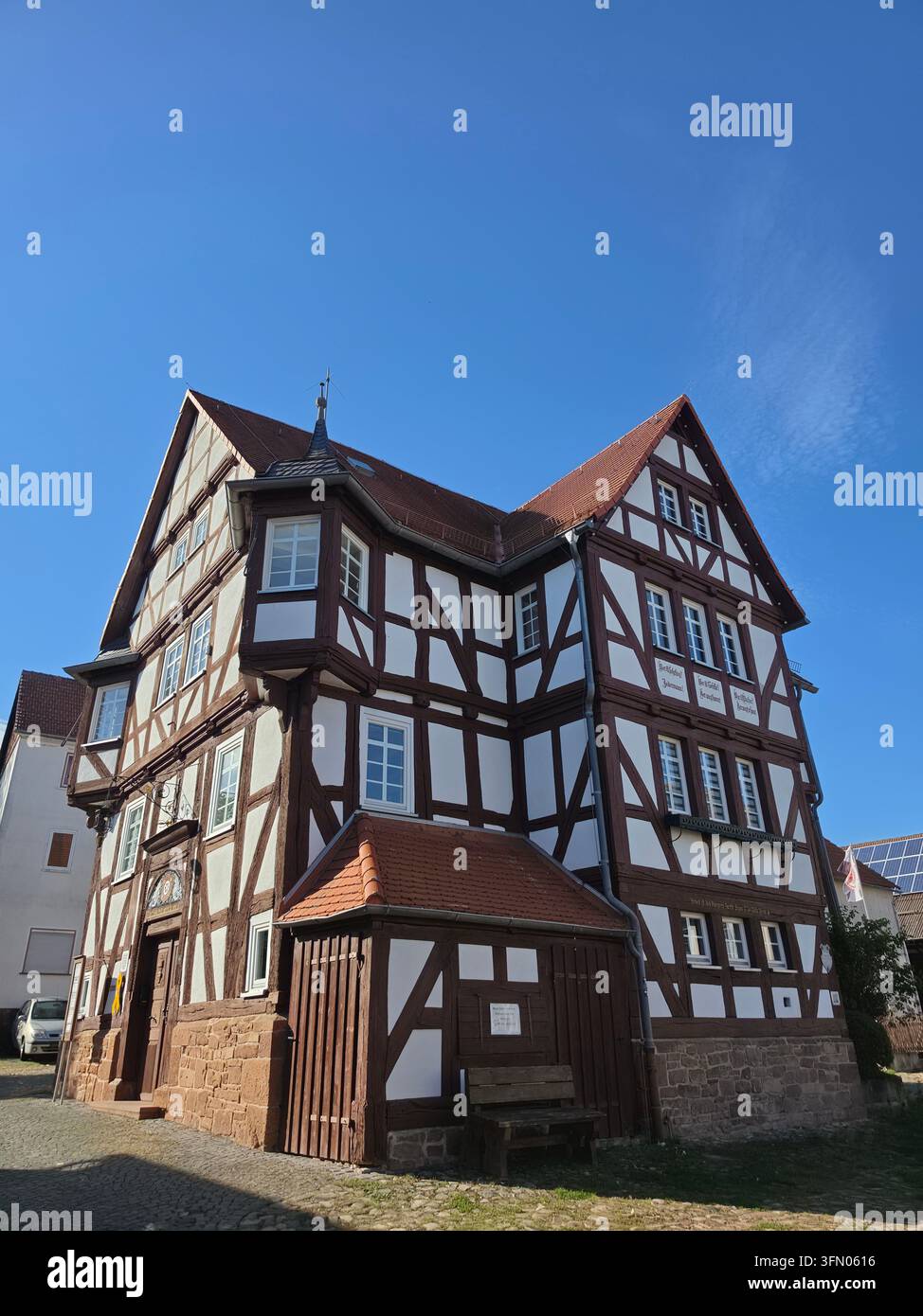 Edificio storico del municipio tradizionale in legno a graticcio contro un cielo blu chiaro in una giornata di sole. - Immagine stock catturata con smartphone