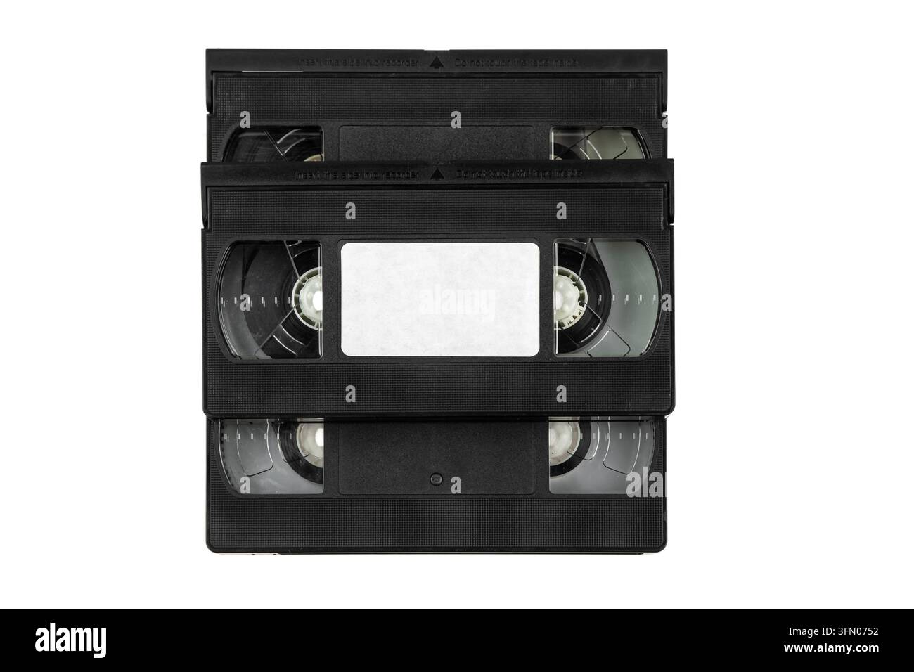 Vista dall'alto di una pila di cassette VHS nere con etichetta vuota isolata su sfondo bianco. Foto Stock