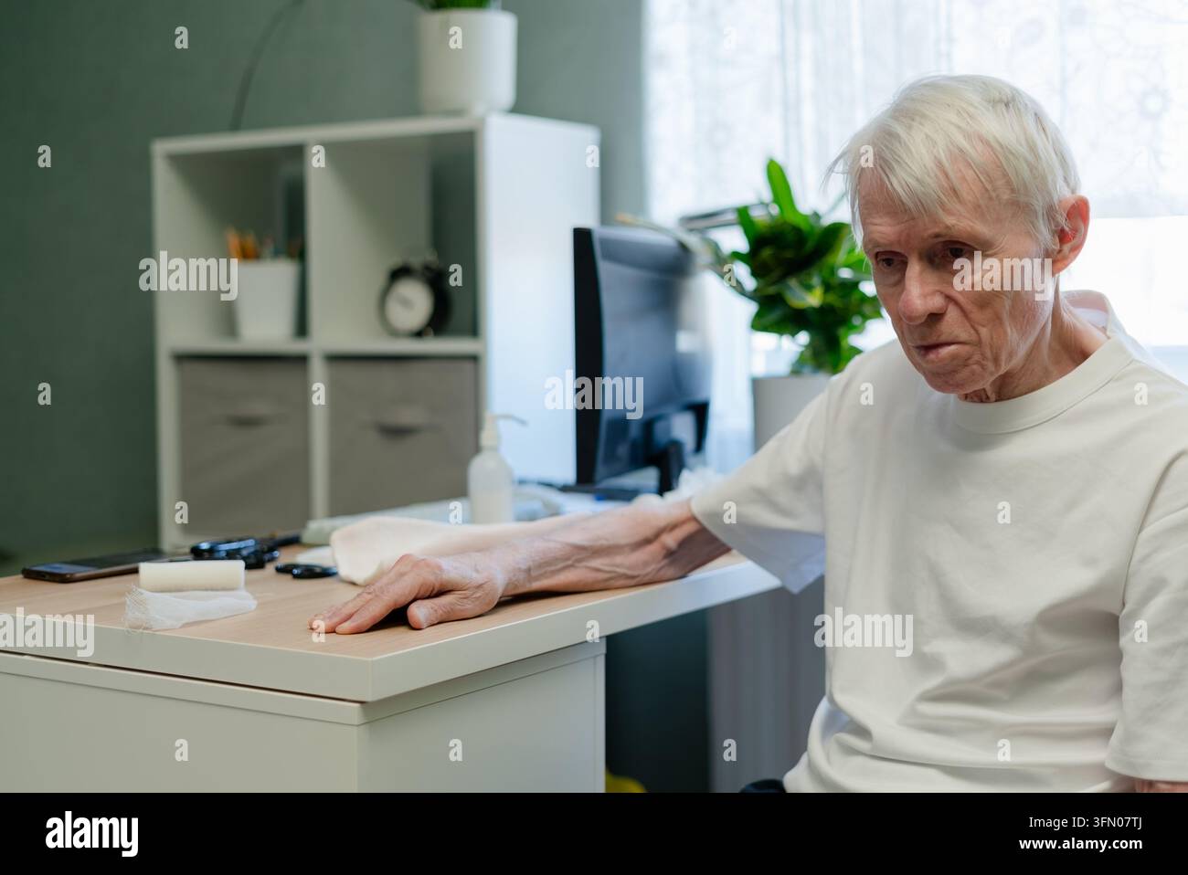 Uomo anziano seduto tranquillamente alla scrivania nello studio del medico in attesa di una consulenza medica. Paziente anziano che partecipa a un appuntamento per il controllo della salute e alla valutazione del benessere nell'ambulatorio della clinica Foto Stock