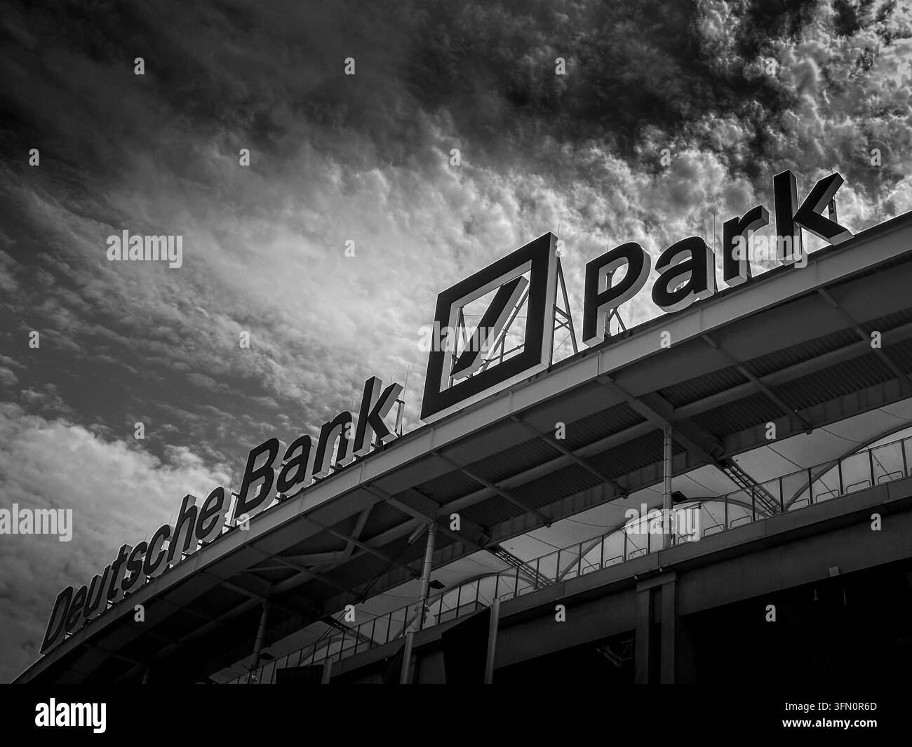 Francoforte sul Meno, Germania - 9 agosto 2026: Vista a bassa angolazione in bianco e nero della facciata curva dello stadio Deutsche Bank Park sotto un cielo drammatico. Foto Stock