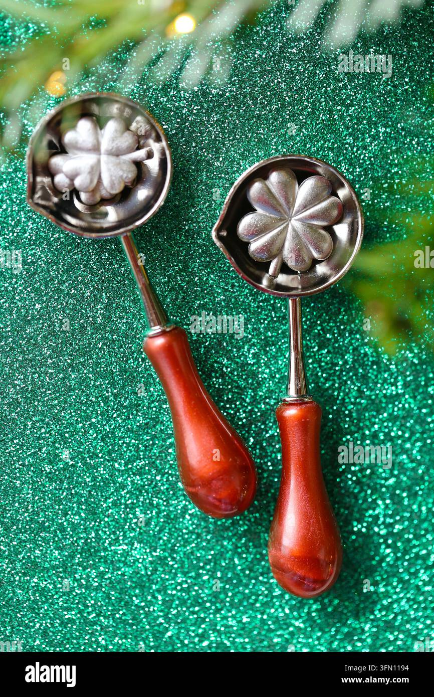 Buon anno nuovo fortunato in cucchiai da versamento in stagno su glitter verde. Gioco di previsione delle feste per celebrazioni familiari, auguri di vacanza, predizione della sorte Foto Stock