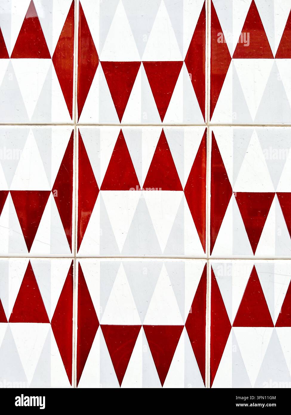 Piastrelle azulejo geometriche rosse e bianche con un motivo a triangolo e rombo su un muro in Portogallo - Immagine stock catturata con smartphone