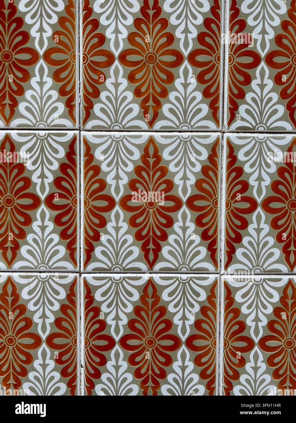Piastrelle azulejo smaltate in Portogallo con un motivo floreale ripetuto arancione ruggine e bianco su fondo verde-grigio - Immagine stock catturata con smartphone