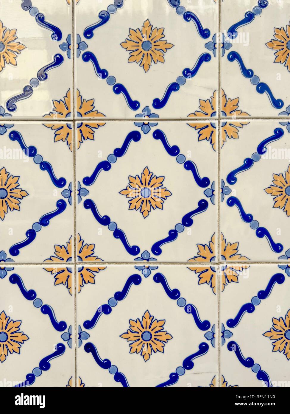 Piastrelle da parete azulejo portoghesi in Portogallo con griglie a voluta blu e rosette floreali arancioni in un motivo ripetitivo Foto Stock